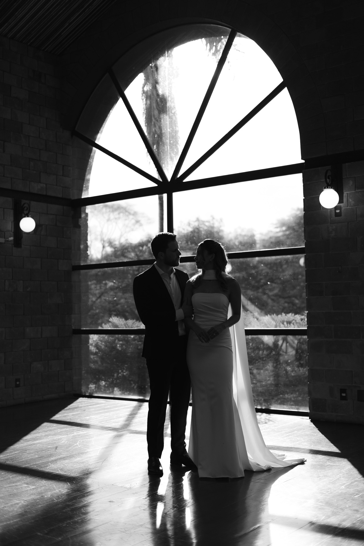 Jorge e Jessica diante de uma janela em arco, em preto e branco
